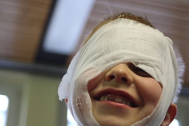 Ein lachendes Kind mit einem verrutschten Kopfverband