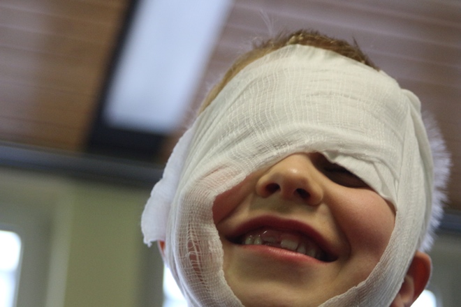 Ein lachendes Kind mit einem verrutschten Kopfverband